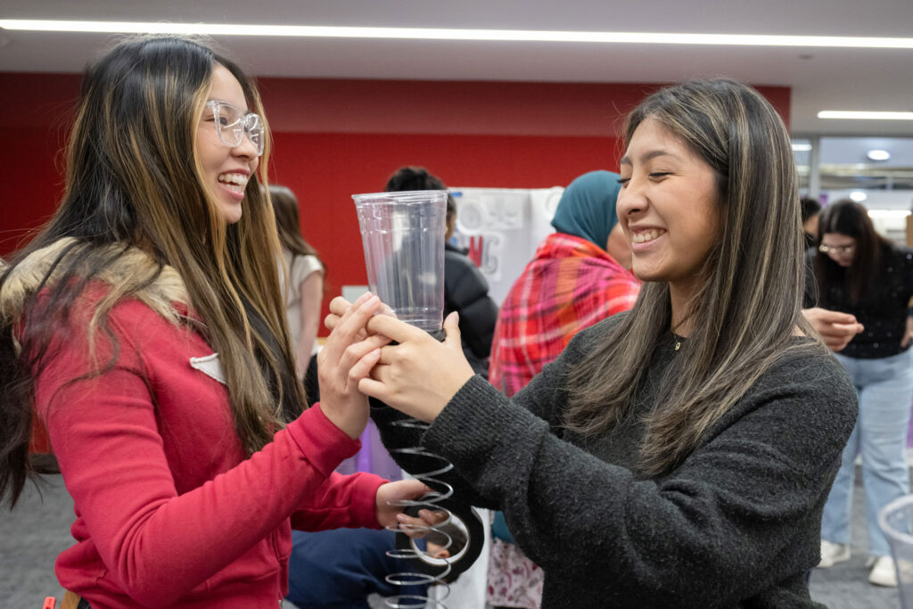 Two people holding up a slinky.
