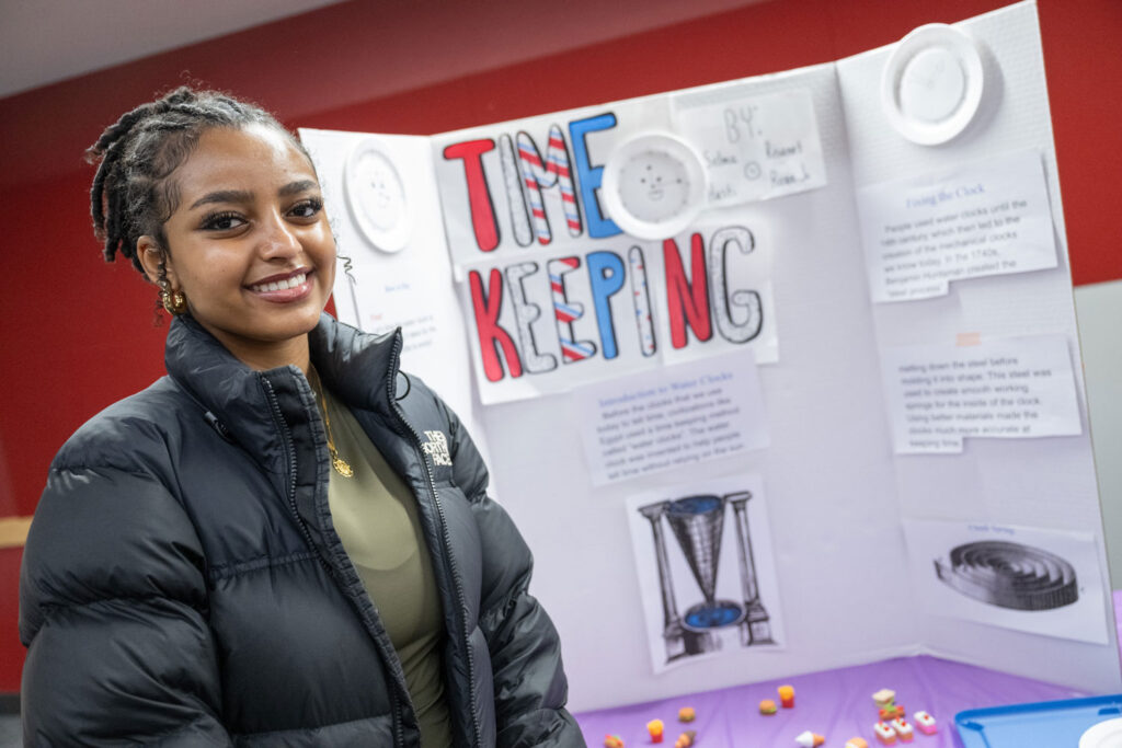 A person next to a poster on timekeeping.