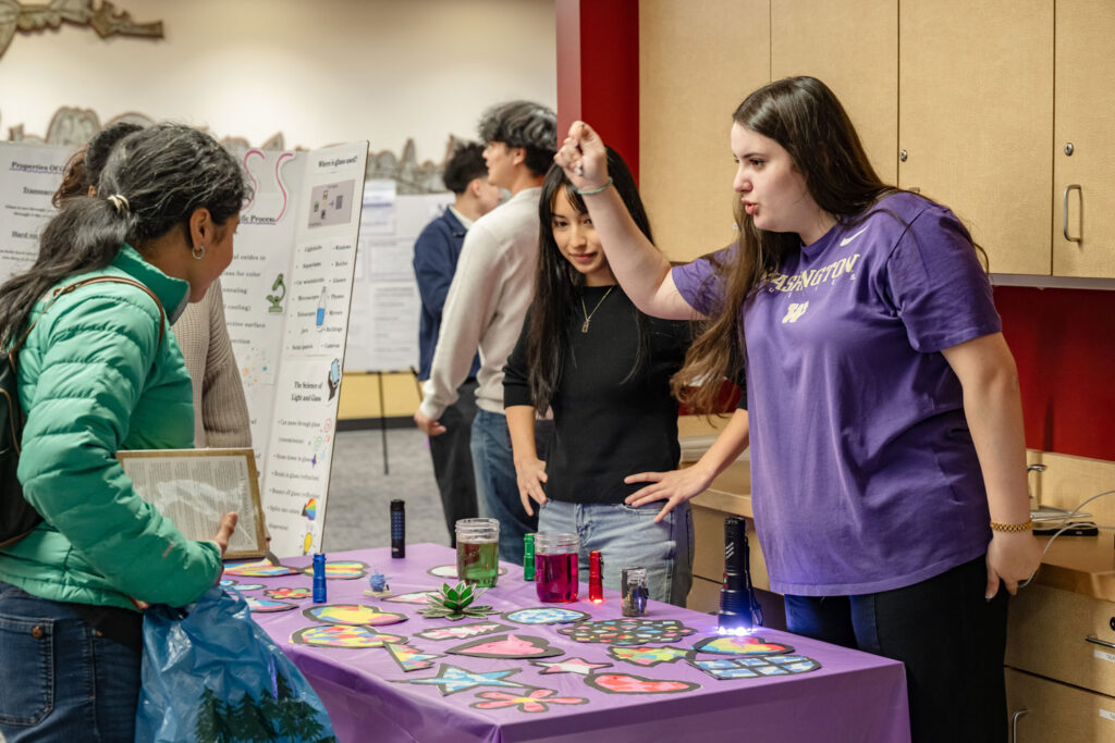 People gathered around a table with art and glasses of colored water.