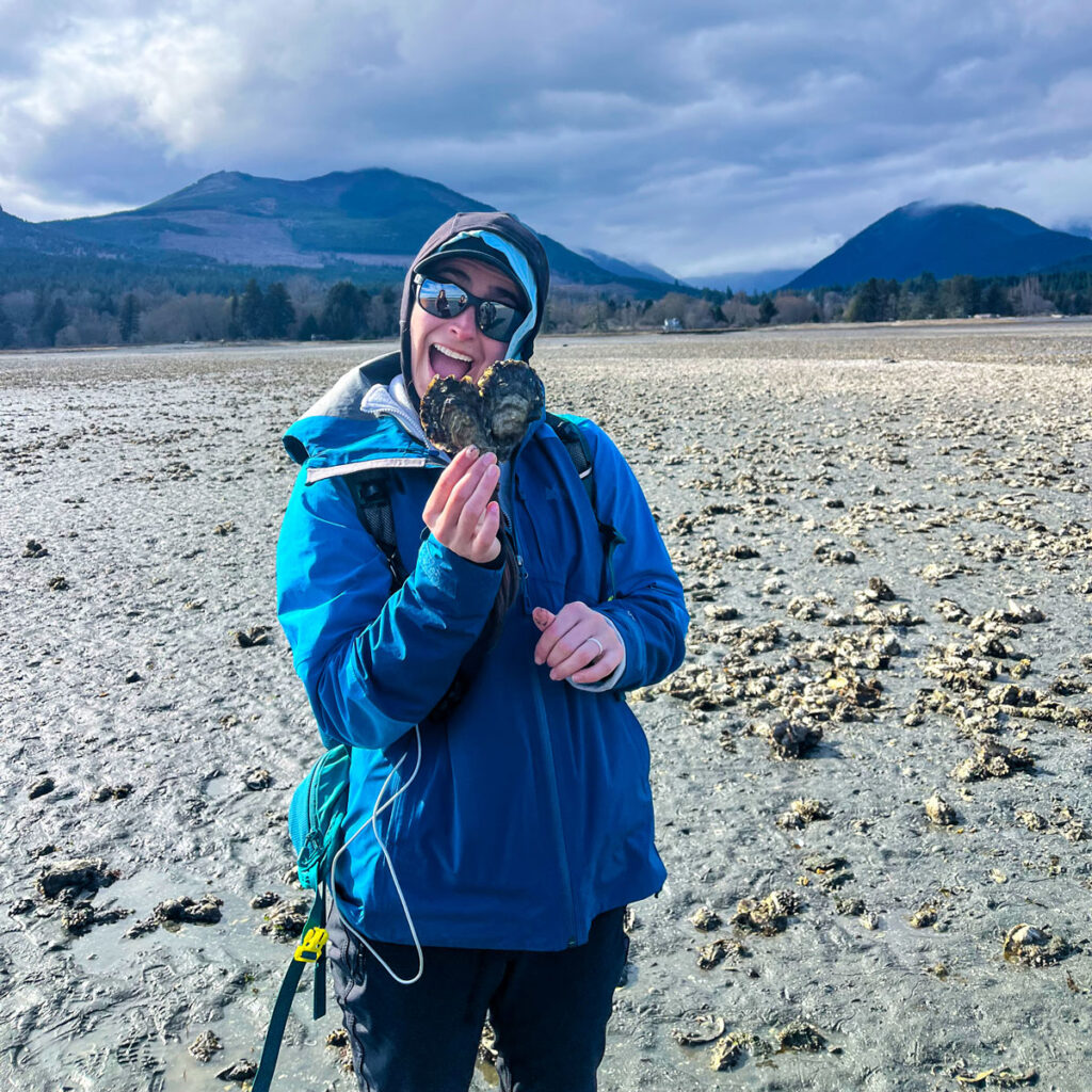 A person holding up an oyster shell.