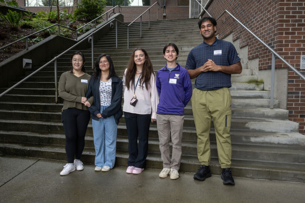 Five people stand in front of a staircase.