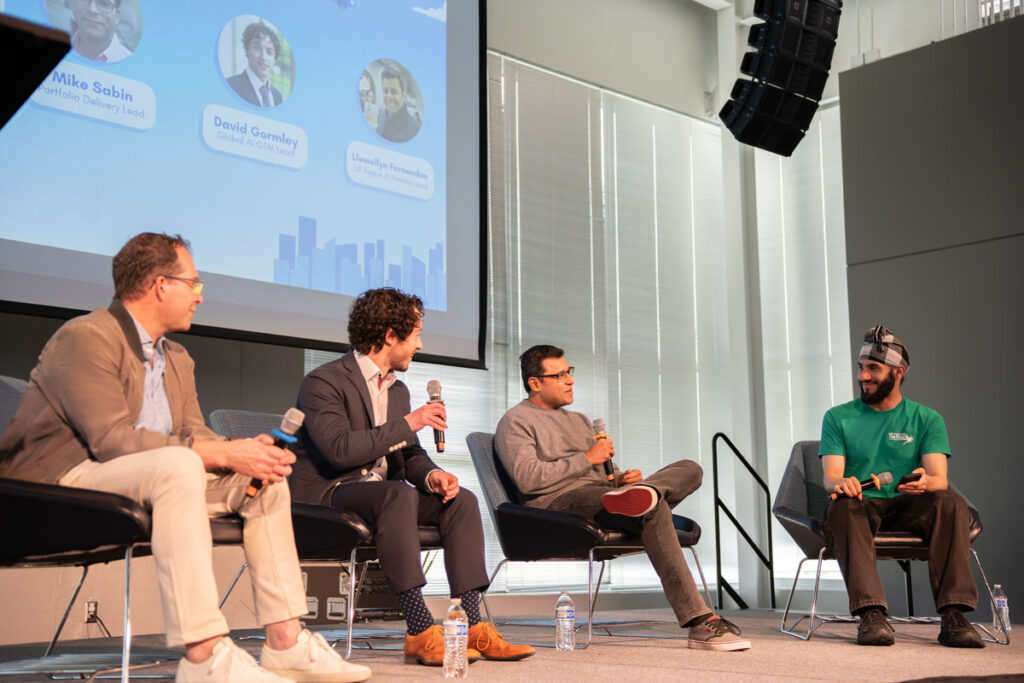 Four people sit on a stage with microphones talking.