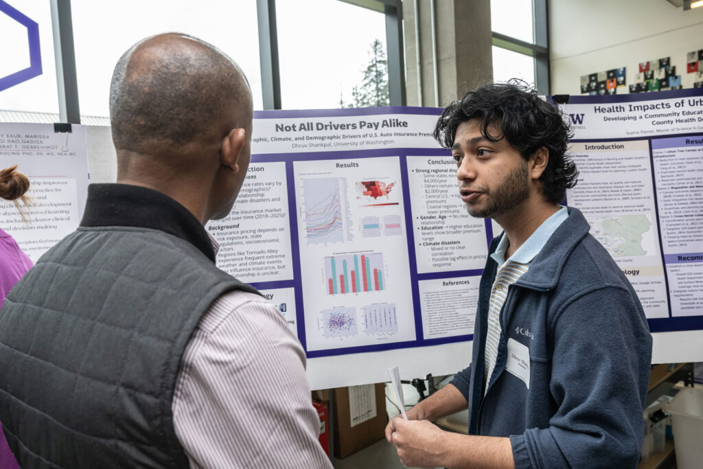 Two people talk in front of a poster.