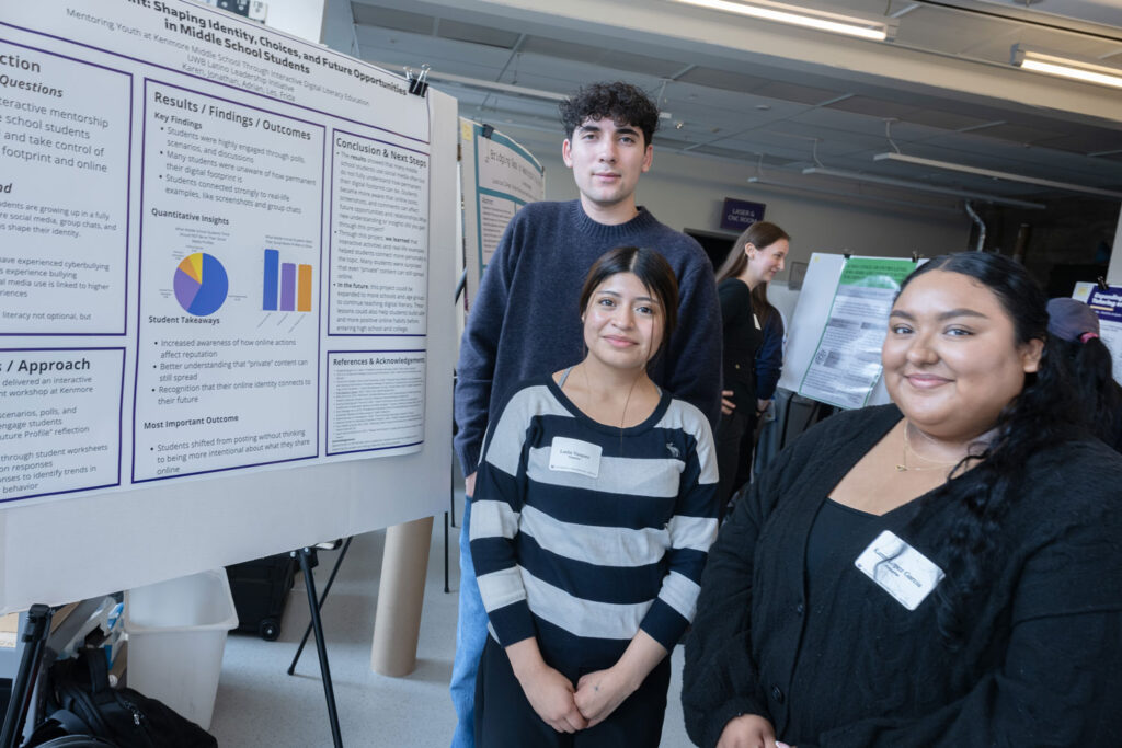 Three people next to a poster.