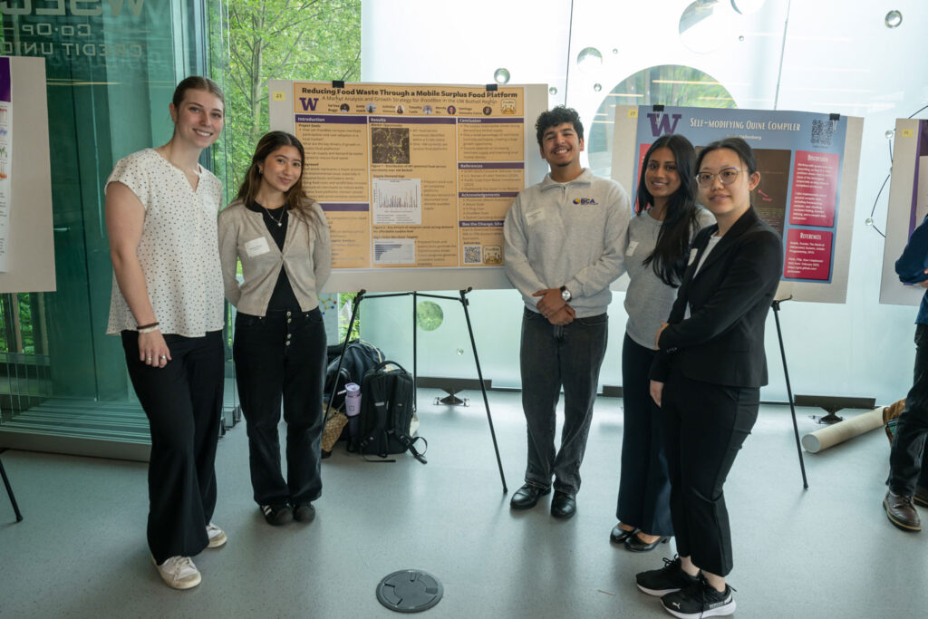 Five people next to a poster.
