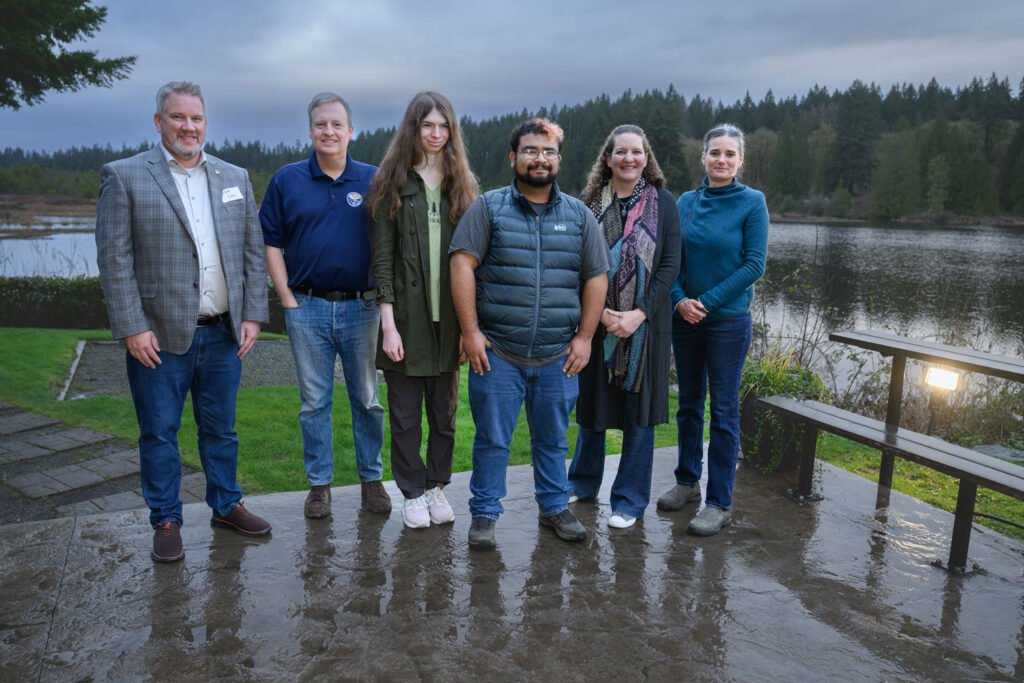 A group of six people stand outside.