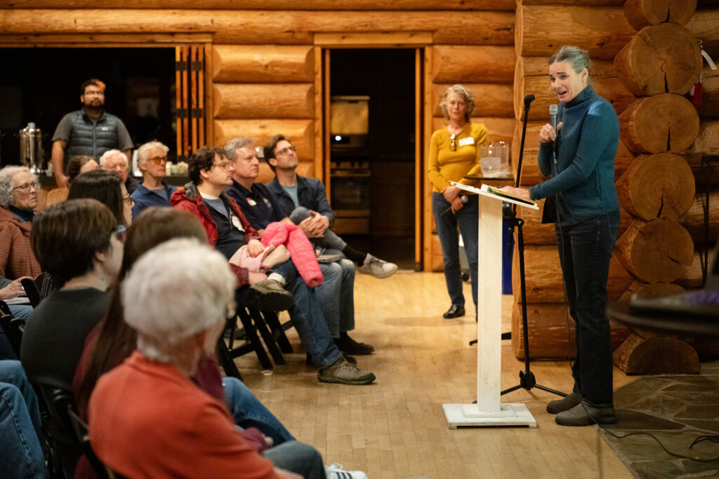 A person speaking at a podium to a crowd of people.