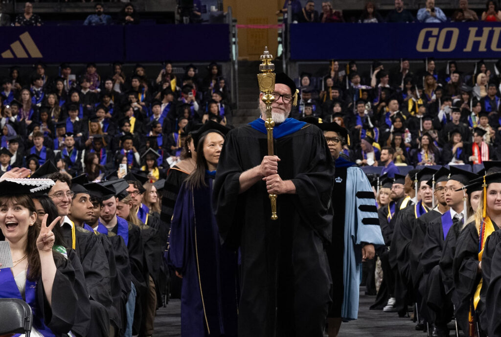 A commencement processional walks down an aisle.