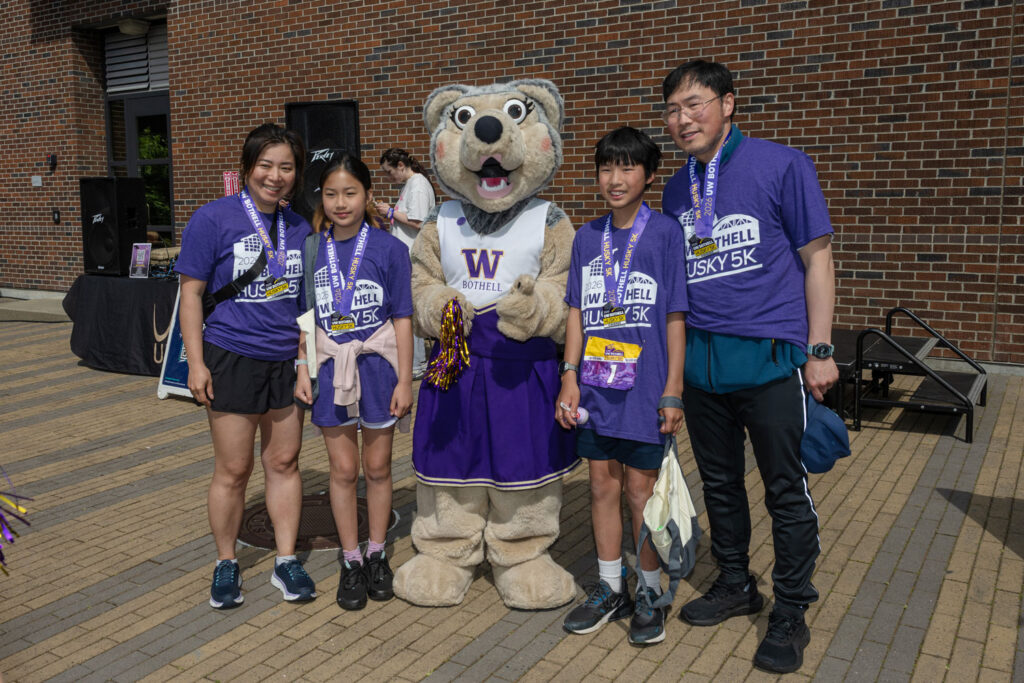 People pose with a husky mascot. 