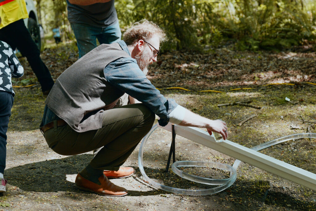 A person crouching down and touching a piece of tubing.