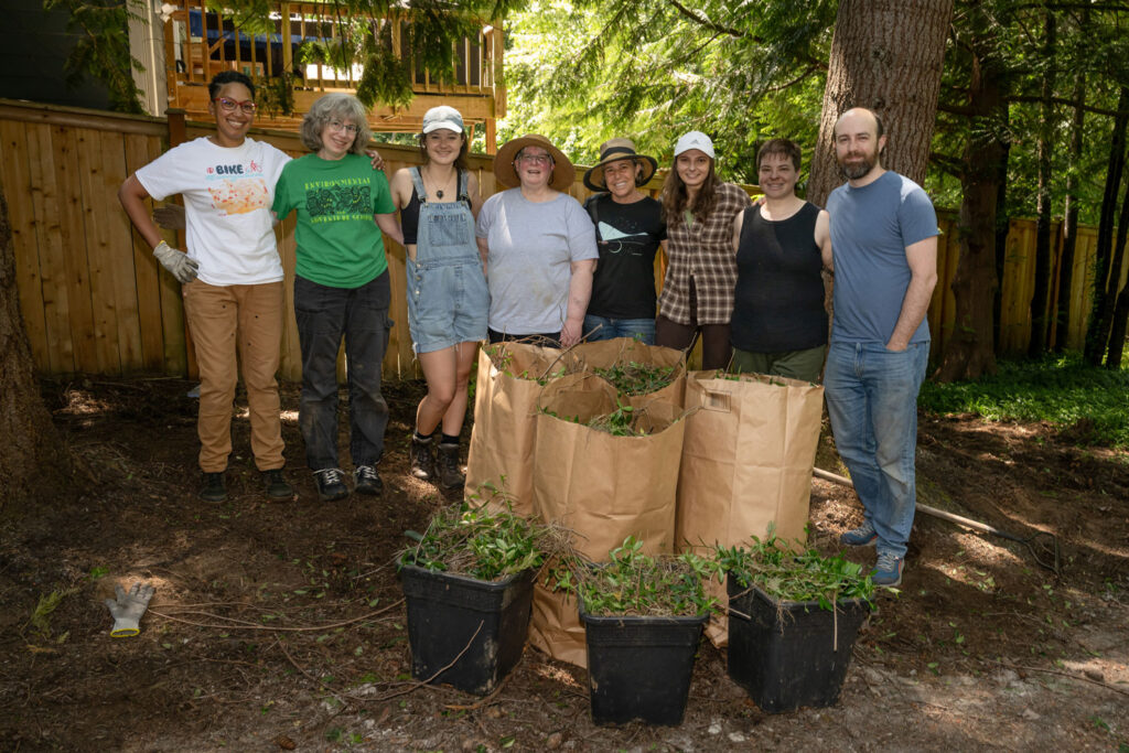 People pose for a photo with backs of yard waste.
