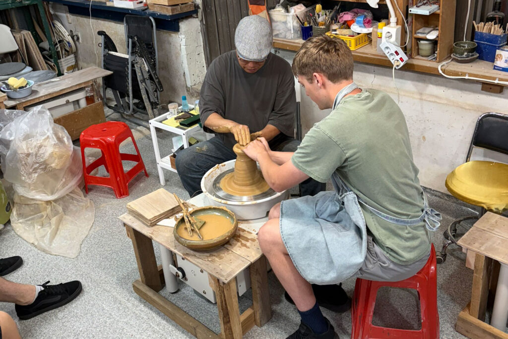 Two people work with a pottery wheel.