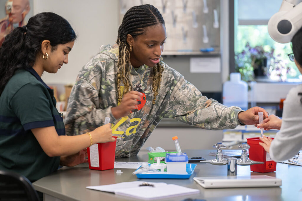 Three people work at a lab table.