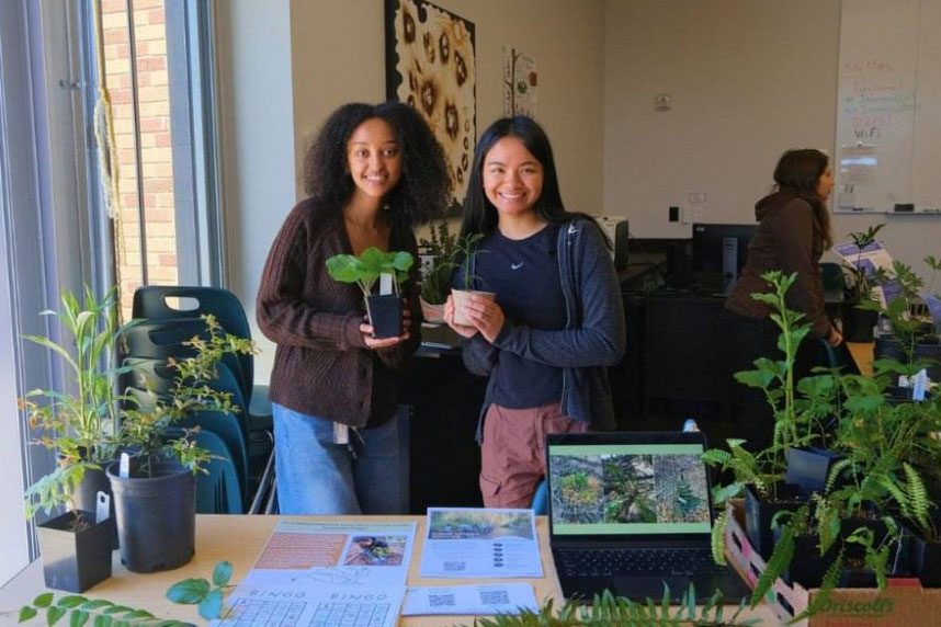 Two people holding up plants.