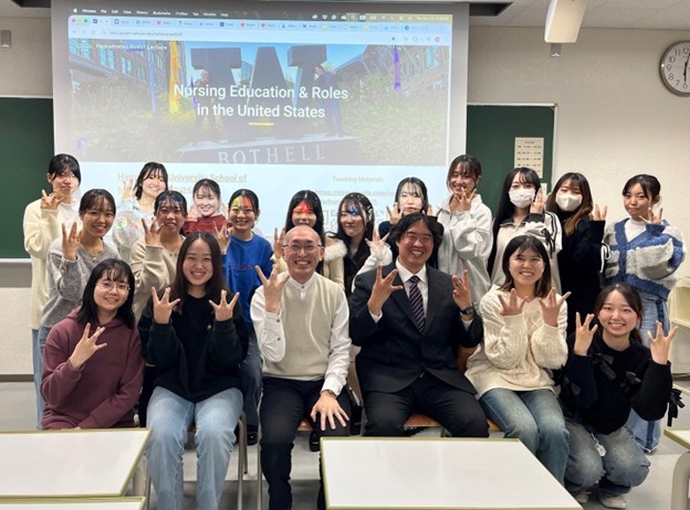 instructors and students pose in front of powerpoint presentation