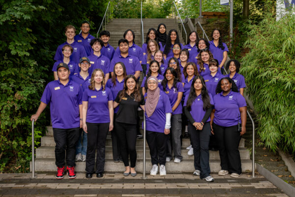 Group photo of 31 peer coaches in purple polos on UWB campus stairs