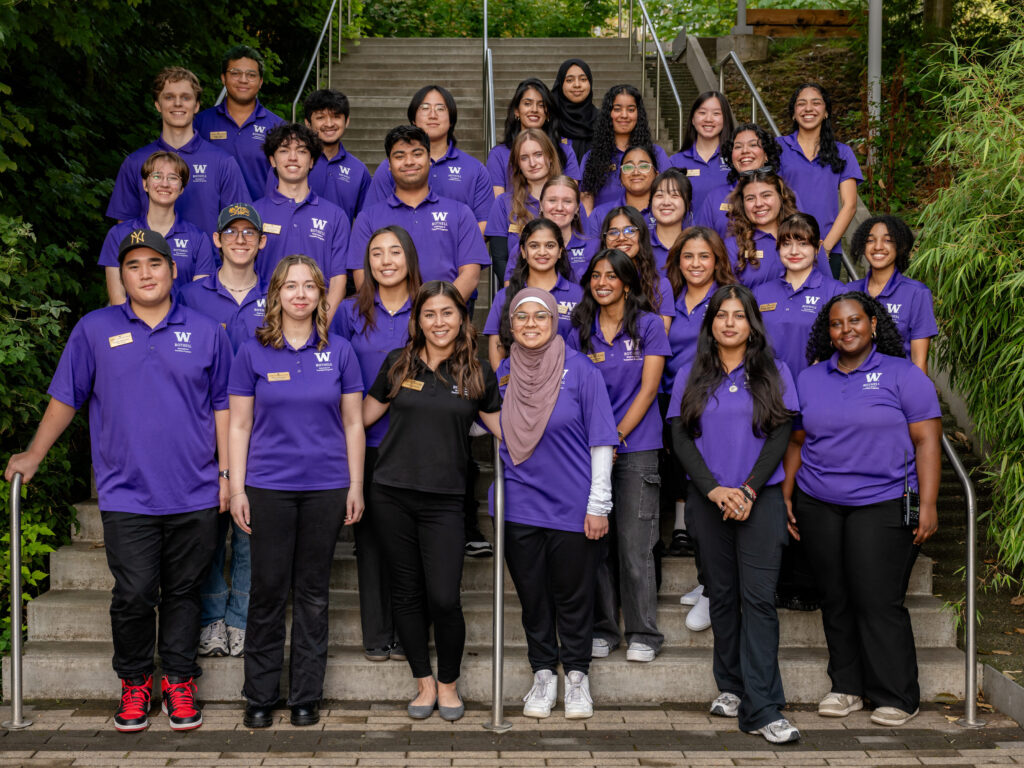 Group photo of 31 peer coaches in purple polos on UWB campus stairs