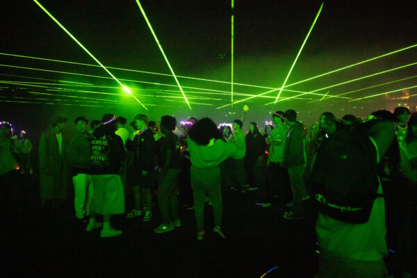 A large group of students under a green laser light show