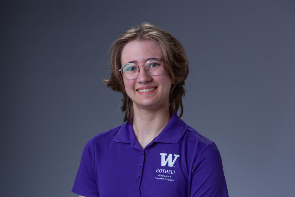 Orientation Leader Easton wearing a purple polo in front of a gray background