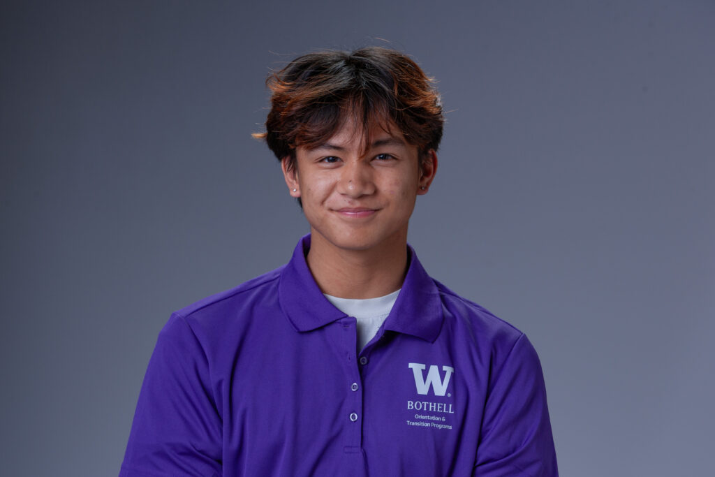 Orientation Leader Zach wearing a purple polo in front of a gray background