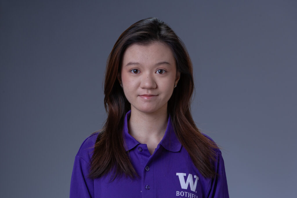 Peer Coach Cindy in a purple polo in front of a gray background