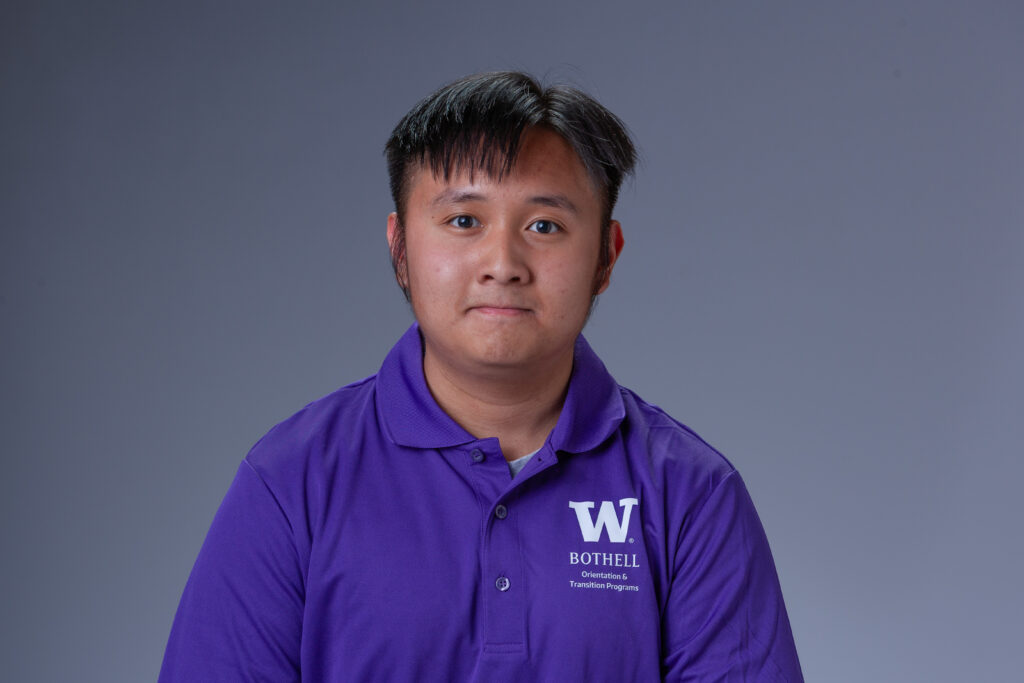 Peer Coach Duy in a purple polo in front of a gray background