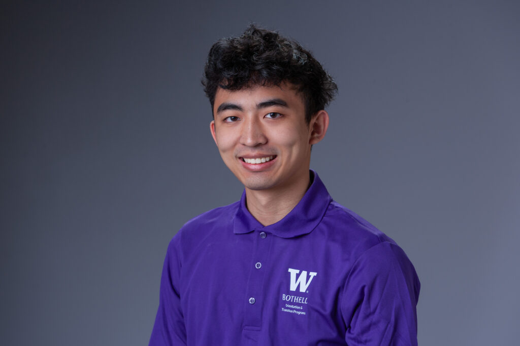 Peer Coach Jake in a purple polo in front of a gray background