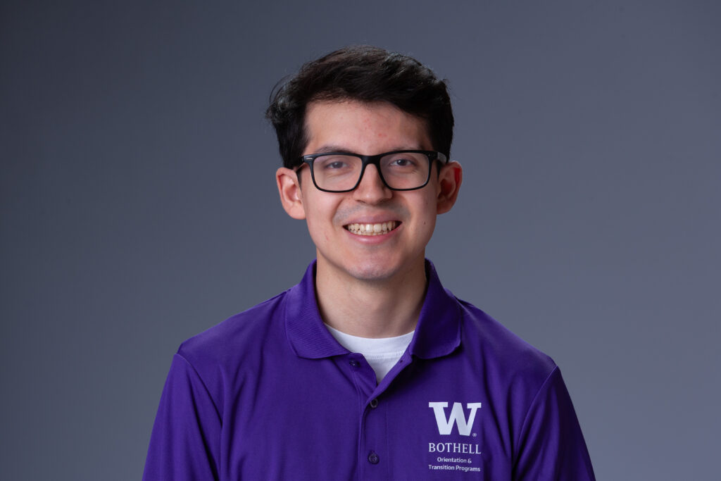 Peer Coach Mauricio in a purple polo in front of a gray background