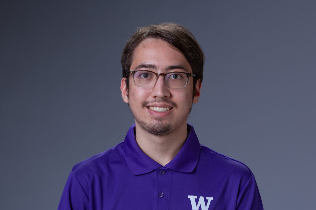 Peer Coach Miles in a purple polo in front of a gray background