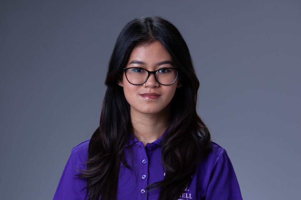 Peer Coach Nikki in a purple polo in front of a gray background
