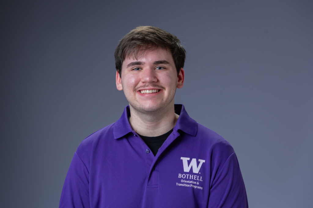 Peer Coach Alex in a purple polo in front of a gray background