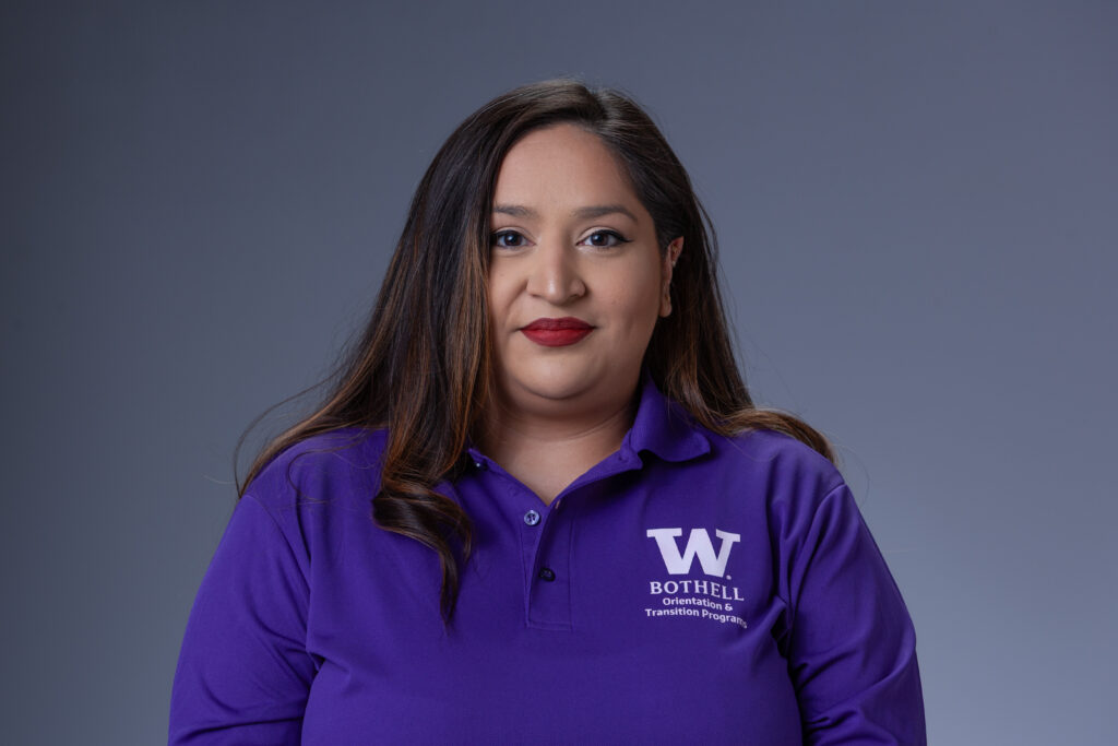 Peer Coach Reena in a purple polo in front of a gray background