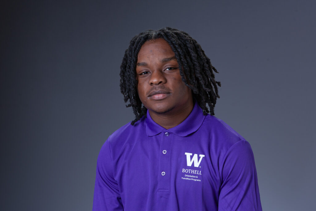 Peer Coach Richard in a purple polo in front of a gray background
