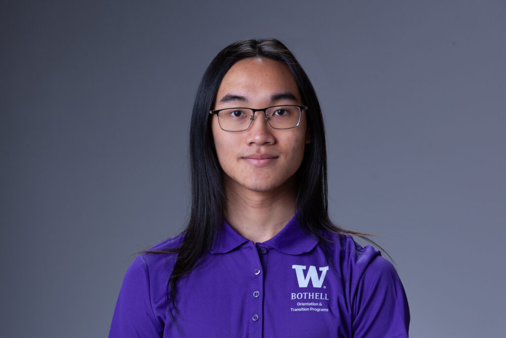 Peer Coach Triton in a purple polo in front of a gray background