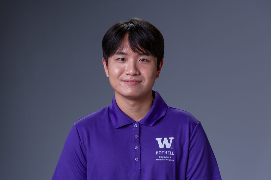 Peer Coach Yoomin in a purple polo in front of a gray background