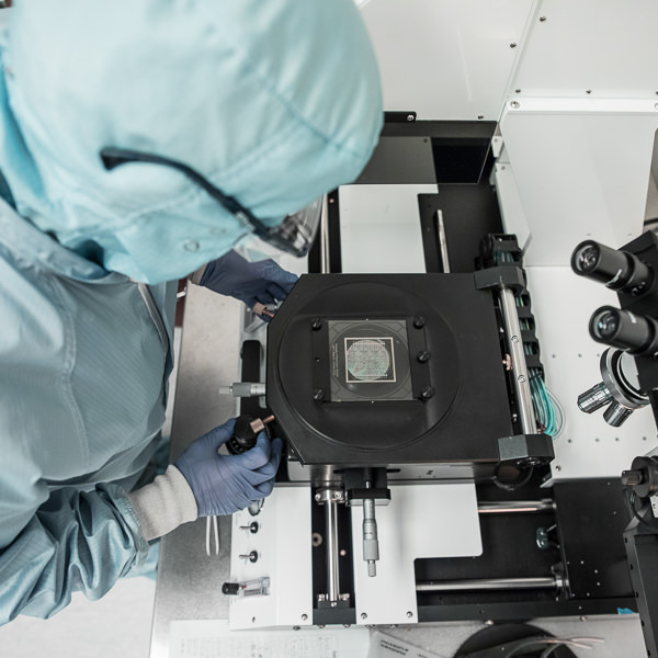 Professor in the clean room in a protective bunny suit, gloved and masked.