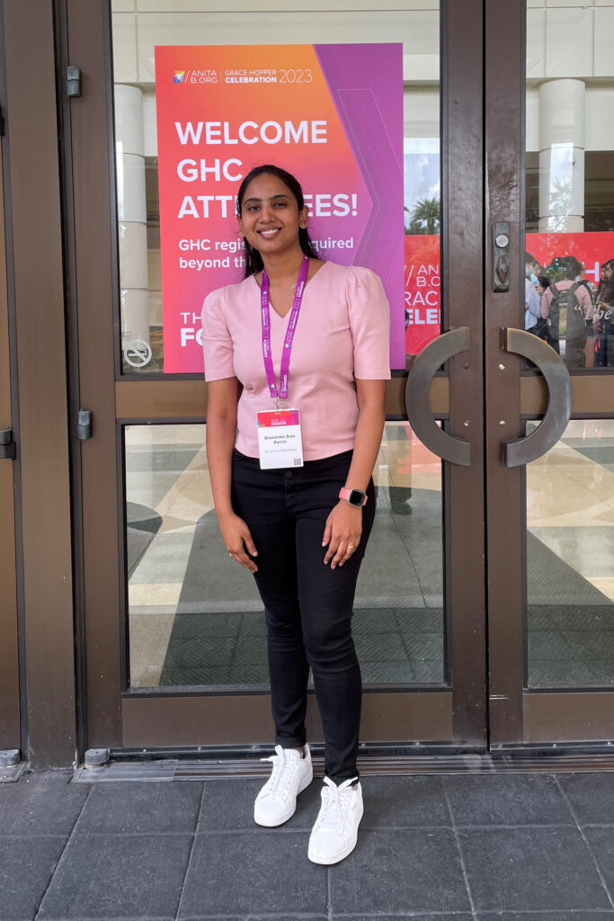 Gresshma Sree Parimi posing in from of the conference entry doors with her badge around her neck.