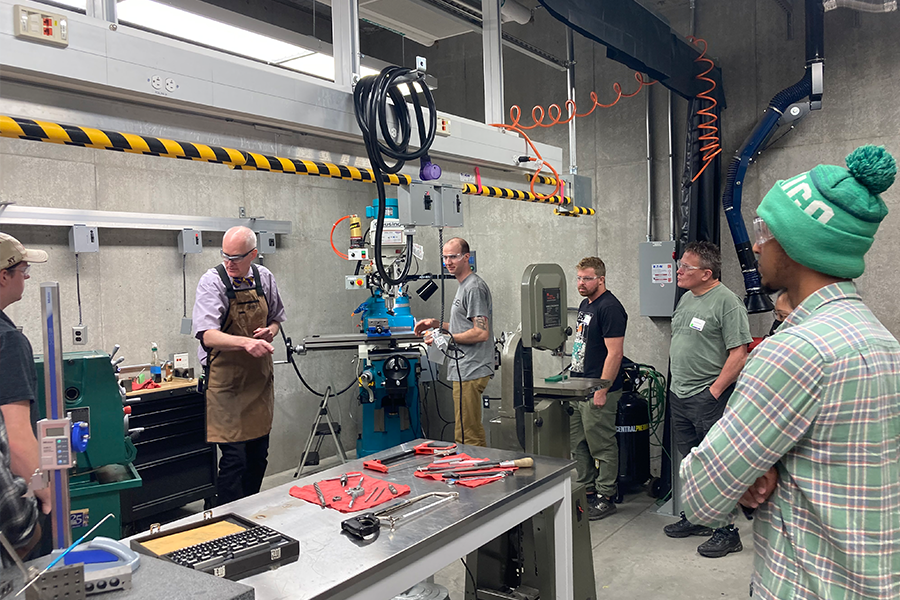 Professor leading a demonstration on machine in the machine shop