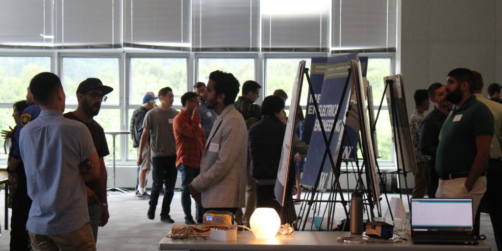 Electrical engineering students demonstrate their capstone projects at a poster session