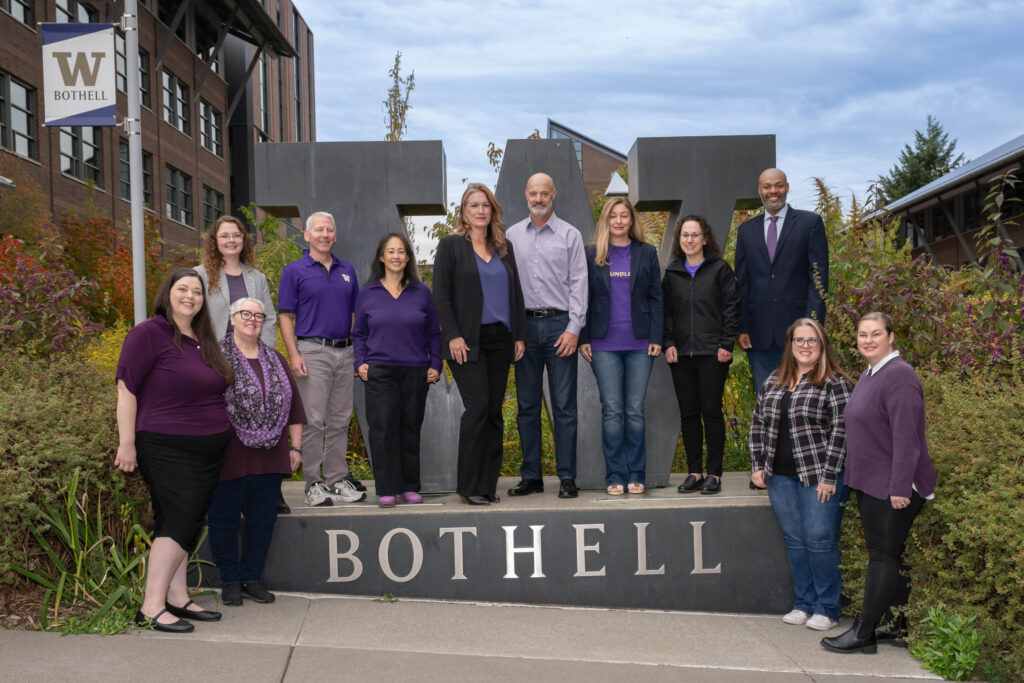 Members of the STEM Advisory Board, wearing purple in spirit, gather by the W Bothell statue for a photo together.