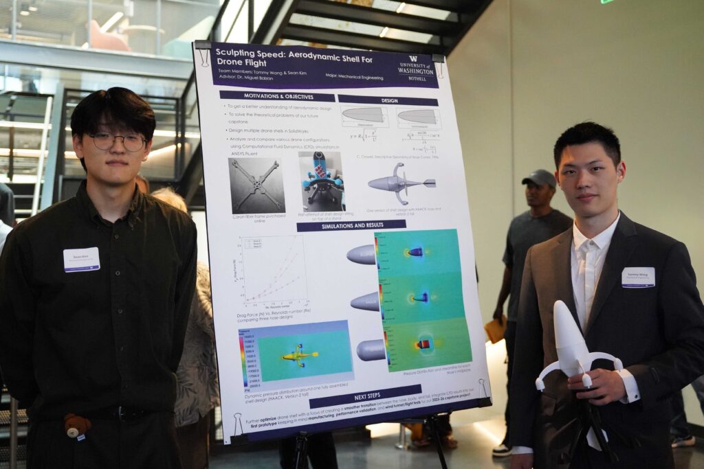 Sean Kim and Tommy Wang next to their poster, holding a model drone.