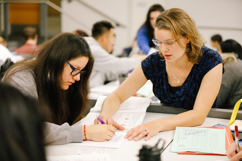 Students in the lab working with beakers of orange, red and green solutions.
