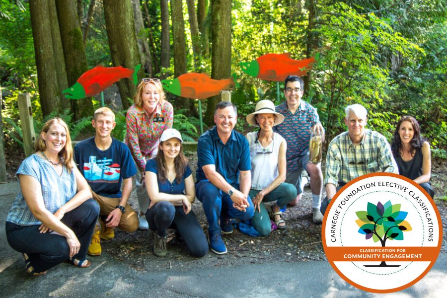 Group of UW Bothell students, staff, and faculty smiling in front of signs of fish