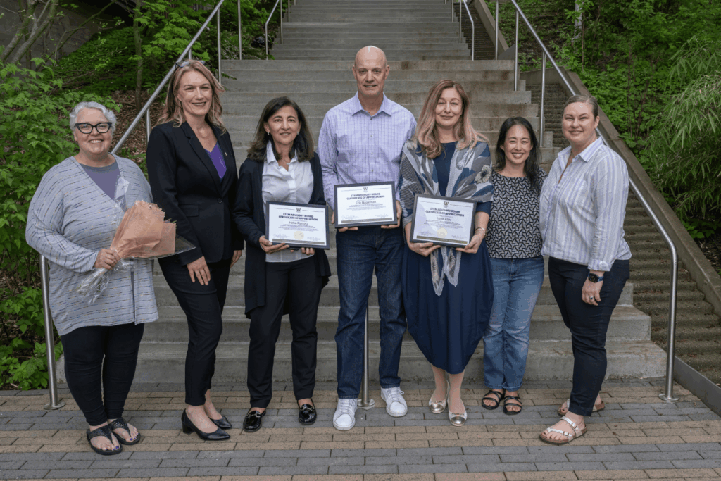 Seven STEM advisory board members on the executive team gather together as the three-emeritus board members hold their certificates for the group photo.