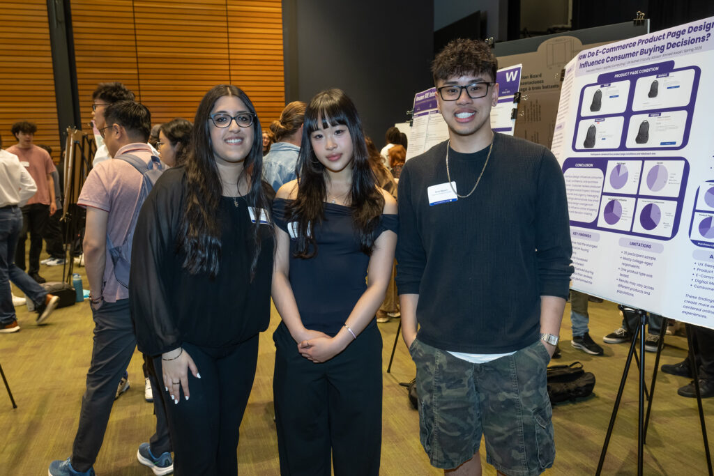 Three students at the symposium with poster boards behind them