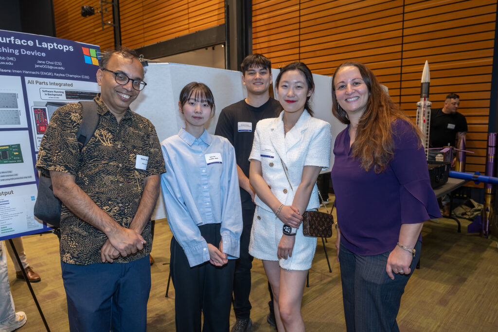 Students and faculty at the symposium, in front of a poster board
