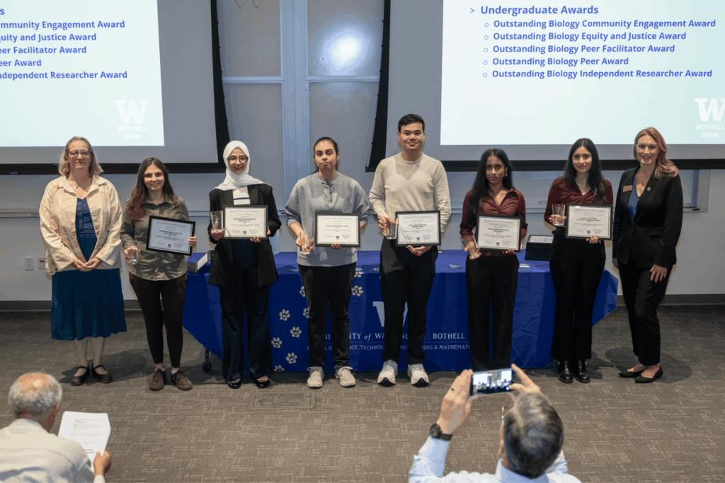 Biological Sciences department awardees holding their certificates, standing in a line with Department Chair Dr. Kristina Hillesland and Dean Jennifer McLoud-Mann