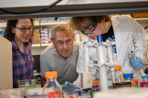 A student, faculty member and an industry partner collaborate together on research in the lab.