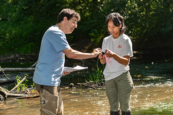 Dr. Jeff Jensen and a student standing in the wetlands while doing research