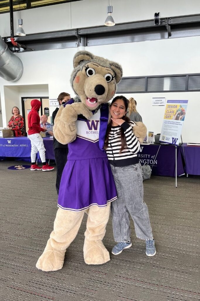 At a UW Bothell event, Jui and Holly the Husky pose for a photo resting their chins on the back of their hands.
